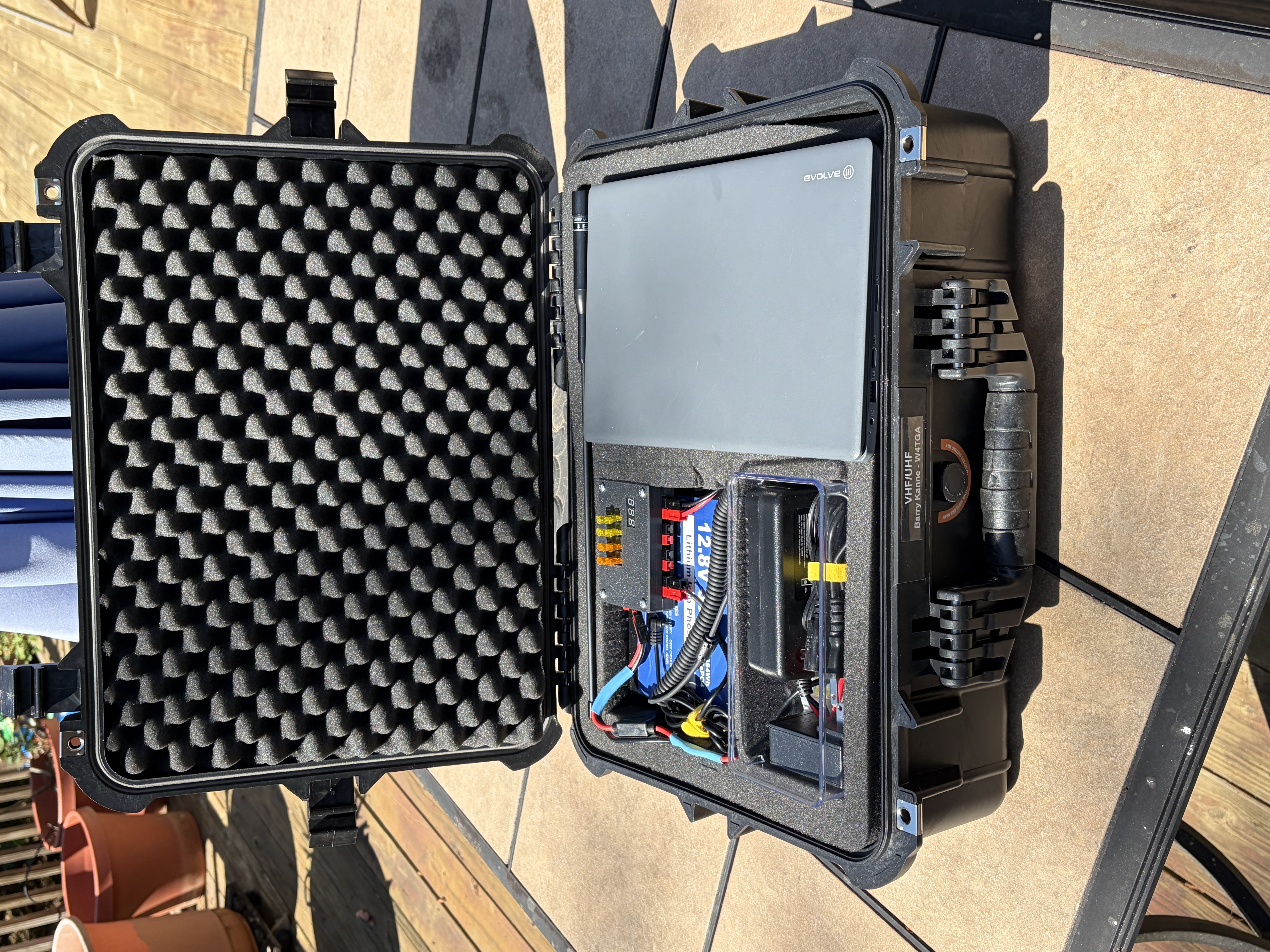 W4TGA's go-kit open from above — LiFePO4 battery, fuse panel, and laptop nested in egg-crate foam inside the Apache case.